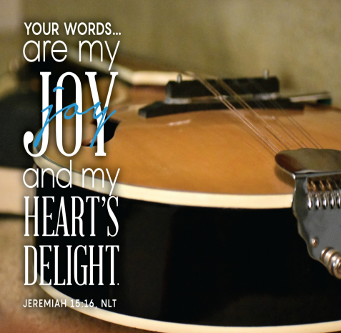 A guitar is laid down on its back and we are looking along it. Text reads: "Your words...are my joy and my heart’s delight."—Jeremiah 15:16
